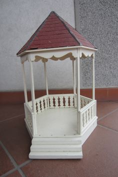 a small white gazebo sitting on top of a tile floor next to a wall