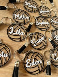 several personalized volleyball key chains with tassels are on a wooden table top