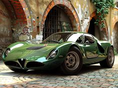 a green sports car parked in front of a brick building with graffiti on it's walls