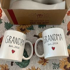 two white coffee mugs with the words grandpa and grandma printed on them in front of a box