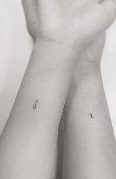 two small tattoos on the wrist that are both black and white, one with an arrow