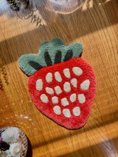 a strawberry shaped rug sitting on top of a wooden table