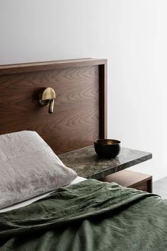 a bed with a wooden headboard next to a bowl on top of the table