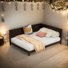 a bed with white sheets and pillows in a room decorated with christmas lights on the wall