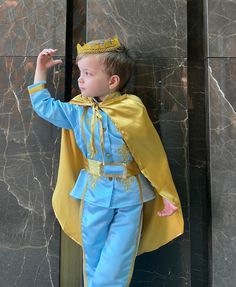 a little boy dressed in a blue and yellow costume with a golden crown on his head