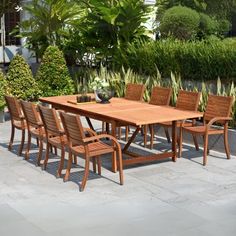 an outdoor dining table and chairs in the middle of a patio with plants around it