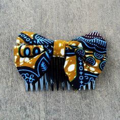 Add a touch of African charm to your wardrobe with this cute hair comb from Ghana. Crafted from cotton by Solace Pearl Anang a bow is printed with blue African designs and leaves against a spotted caramel background. The comb is made from recycled plastic to secure this eco-friendly hair accessory. Caramel Background, Blue Foliage, Handcrafted Beaded Jewelry, Cotton Hair, African Designs, Gift Suggestions, Fabric Accessories, African Wax Print, Cute Hair