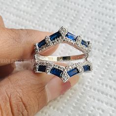 a woman's hand holding two rings with blue stones