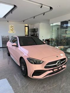 a pink car is parked in a showroom