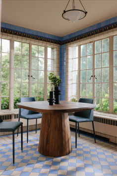 a dining room with blue chairs and a table in front of large windows that look out onto the woods