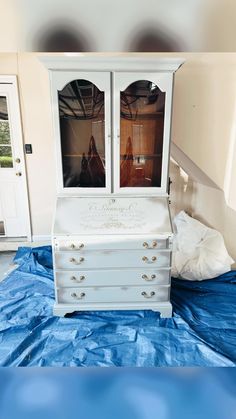 a white dresser sitting on top of a blue tarp