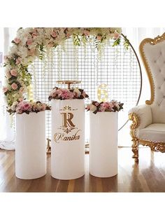 three white vases with flowers in them sitting on a wooden floor next to a chair