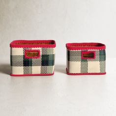 two woven baskets sitting next to each other on a white surface with red trimmings