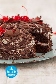 a piece of cake with chocolate frosting and cherries on top is sitting on a plate