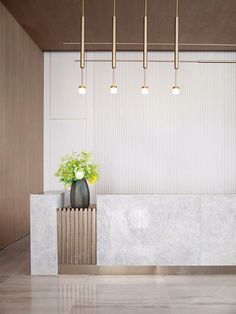 a white marble counter with a plant in it and four lights hanging from the ceiling