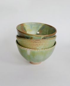 three bowls are stacked on top of each other in green and brown tones, one is empty