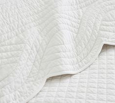 an unmade bed with white quilting on it