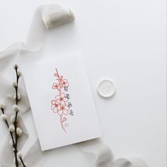 a white card with red flowers on it next to a wax stick and some cotton