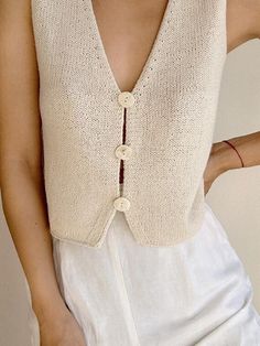 a woman wearing a white top with buttons on it