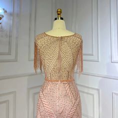 a dress on a mannequin in front of a white wall with gold trim