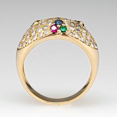 This posh ring is accented with sixty-eight (68), bead set, round brilliant cut diamonds, three (3), shared prong set, round mixed cut natural blue sapphires, three (3), shared prong set, round mixed cut natural emeralds and three (3), shared prong set, round mixed cut natural rubies. The ring measures 10.8mm at the top, rises 4.9mm above the finger, tapering to 4.2mm wide and 1.1mm thick at the base of the shank. This ring is currently a size 7. Blue Sapphire Ring, Bead Set, Blue Sapphire Rings, Natural Blue Sapphire, Natural Ruby, Natural Emerald, Round Brilliant Cut Diamond, Brilliant Cut Diamond, Round Brilliant