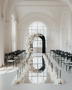 an indoor wedding ceremony with white flowers and black chairs