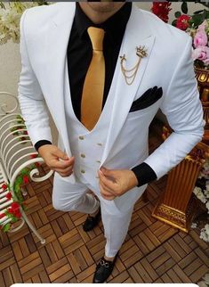 a man in a white suit and gold tie posing for the camera with his hands on his hips