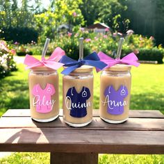 three jars filled with peanut butter sitting on top of a wooden table in the grass