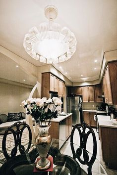 a vase with flowers sitting on top of a glass table in a living room next to a kitchen