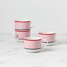 two pink and white coffee cups sitting on top of a marble counter next to each other