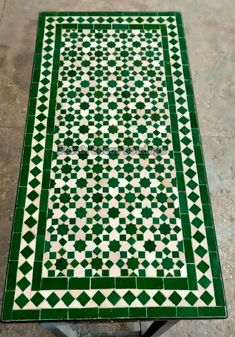 a green and white tile table with an intricate design on it's top,