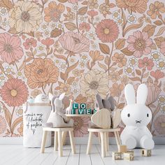 two small wooden chairs sitting next to each other in front of a floral wallpaper