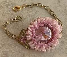 a close up of a bracelet with beads and a pink flower on it's chain