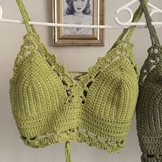 two crocheted bras hanging on a clothes line next to a framed photo