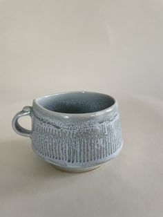 a white and gray cup sitting on top of a table