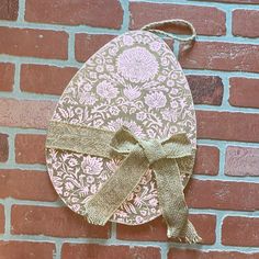 a paper plate with a bow hanging on a brick wall