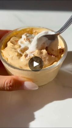 a hand holding a spoon with some ice cream in it on a white counter top