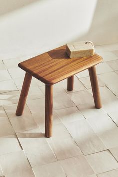 a small wooden table with a piece of wood on it's top sitting on a white tiled floor