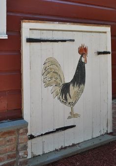 a chicken painted on the side of a building next to a brick wall and door