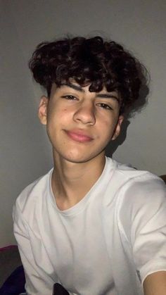 a young man with curly hair wearing a white shirt