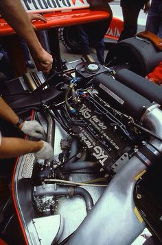 the engine compartment of a race car being worked on by some mechanics and workers at work