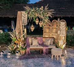 an outdoor seating area with wicker furniture and flowers on the table, in front of a gazebo