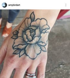 a woman's hand with a flower tattoo on it