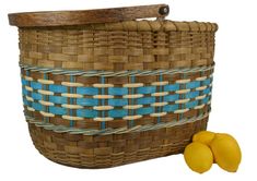 two lemons sitting next to a basket with blue strips on the handles and sides