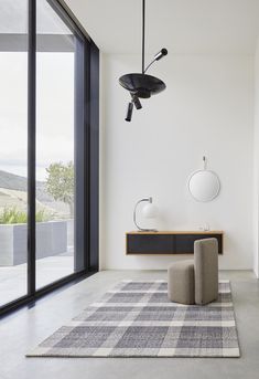 a modern living room with large windows and an area rug on the floor that has a checkered pattern