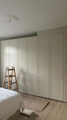 an empty bedroom with white walls and wooden flooring, including a ladder in the corner