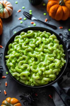 green macaroni and cheese in a black bowl with sprinkles on the side