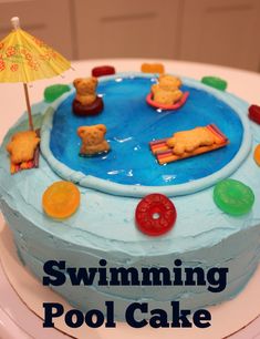 there is a swimming pool cake on the table with an umbrella and toy bears in it