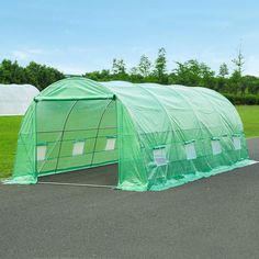 a large green house sitting on top of a parking lot next to a lush green field