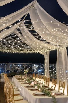 the tables are set up with white linens and lights strung over them for an outdoor wedding reception